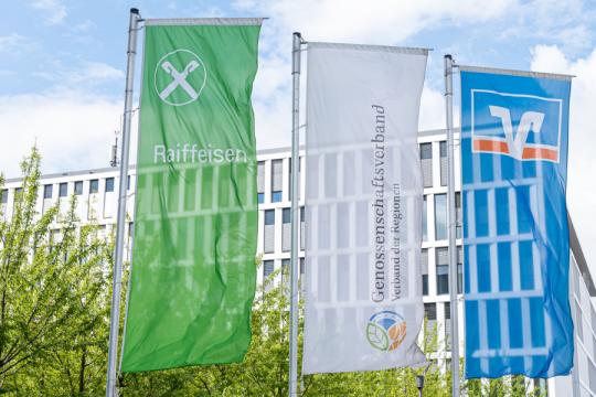 3 Flaggen mit Logos nebeneinander: Raiffeisen, Genossenschaftsverband und VR-Bank