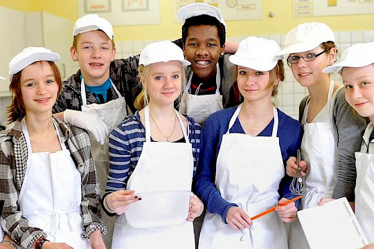 Schülerinnen und Schüler in Kochschürzen